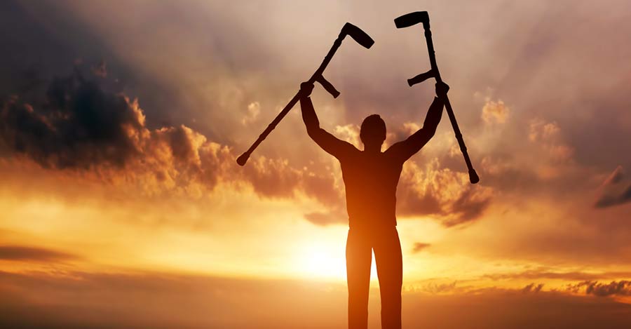 worldcrutches-Man-with-crutches-raised-in-both-hands-at-sunset